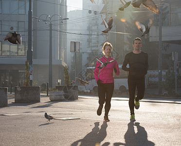 健康的轻夫妇清晨城市慢跑,背景日出图片
