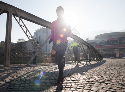 运动的女人跑步人行道上清晨慢跑与城市日出的背景图片