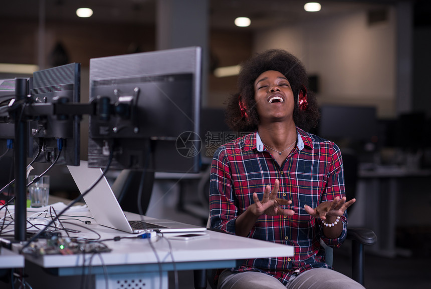 轻的黑人妇女她的工作场所创业公司的办公室听音乐耳机演奏乐器,同时放松图片