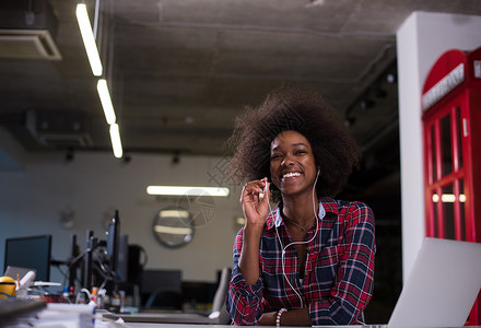 黑人办公她的工作场所,现代办公室里的黑人妇女电话上耳机笔记本电脑工作背景