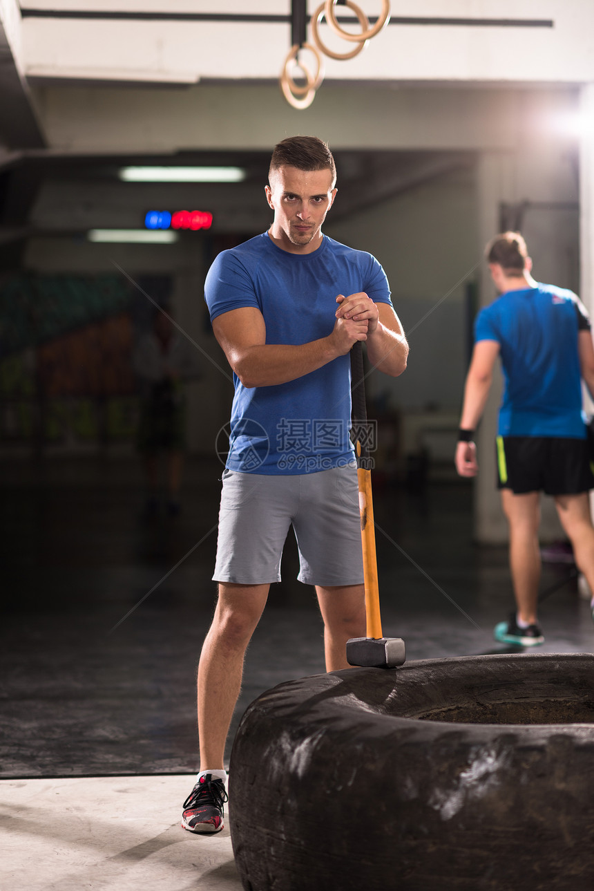 大锤轮胎用拖拉机轮胎健身房锻炼轻的肌肉男图片