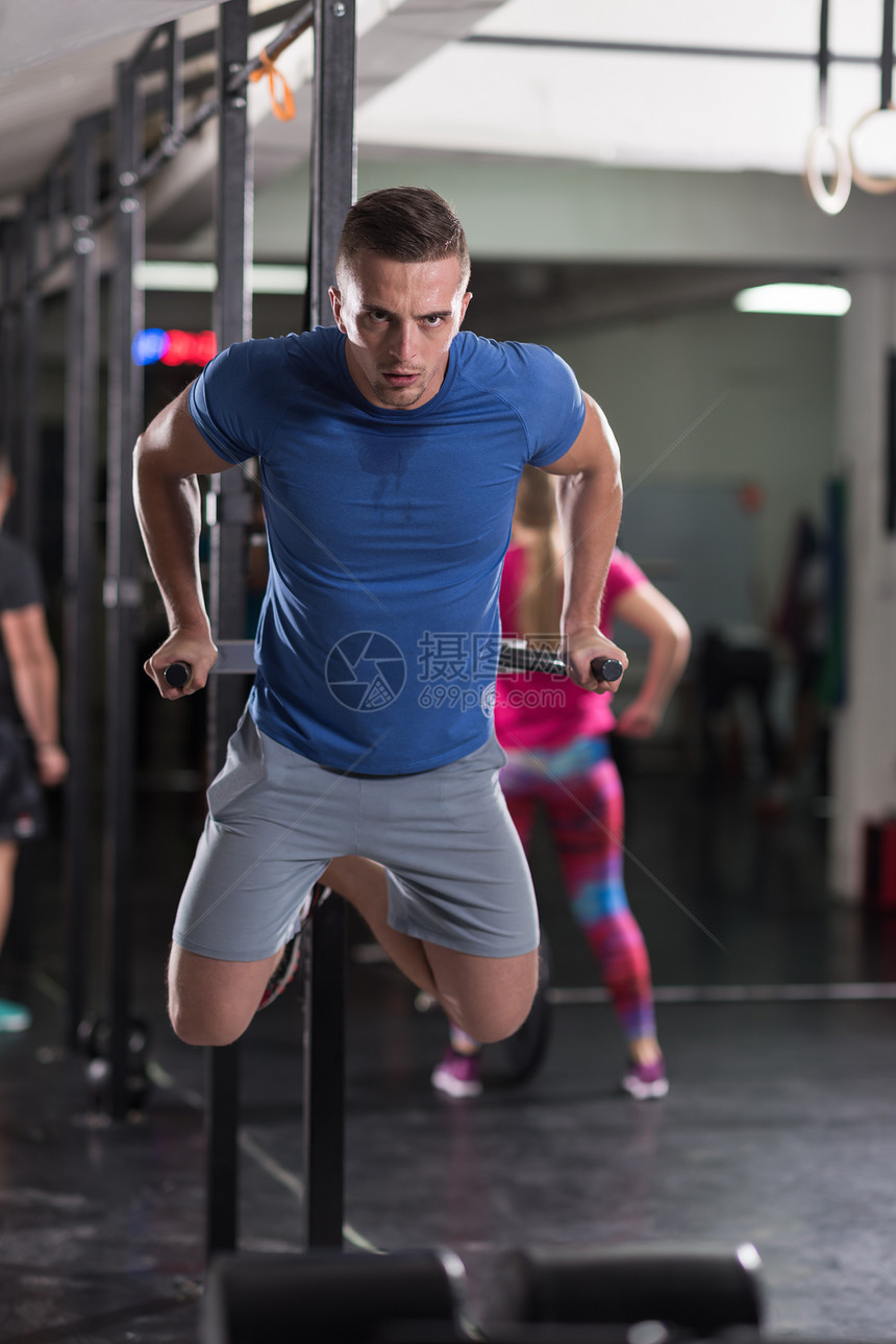 轻的肌肉健美运动员健身房锻炼,双杠运动图片
