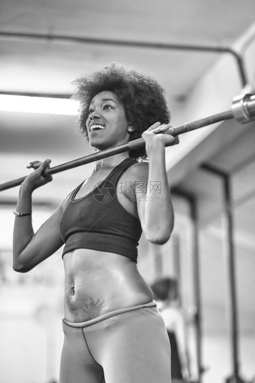 轻可爱的非裔美国运动妇女健身房举空酒吧图片