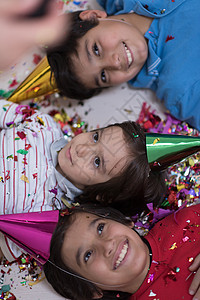 快乐的孩子们边躺地板上边用纸屑庆祝聚会图片