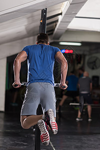 轻的肌肉健美运动员健身房锻炼,双杠运动图片