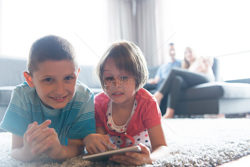 快乐的轻家庭家里玩孩子们地板上用平板电脑图片