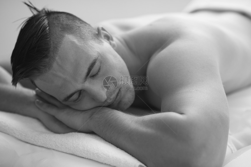 迷人的英俊男人休息水疗按摩中心,躺桌子上放松闭着眼睛的男人美容保健图片