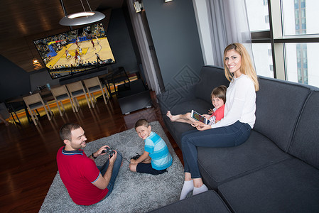 幸福的家庭爸爸妈妈孩子们地板上玩篮球电子游戏图片