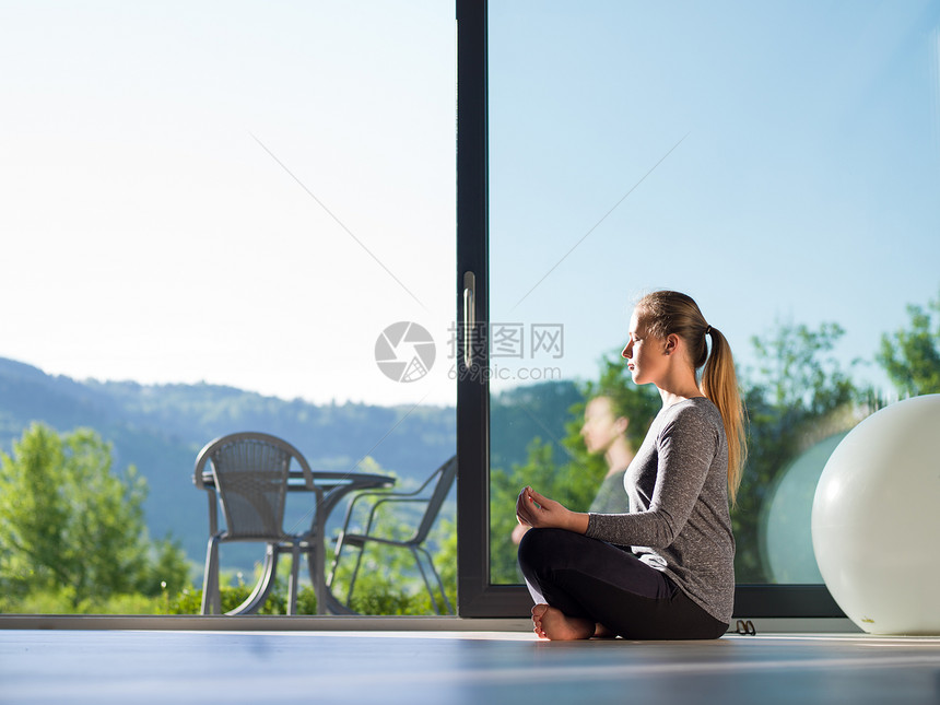 个轻英俊的女人她豪华的别墅地板上瑜伽练图片