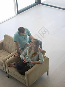 轻夫妇豪华的家里放松,平板电脑客厅沙发上看书图片