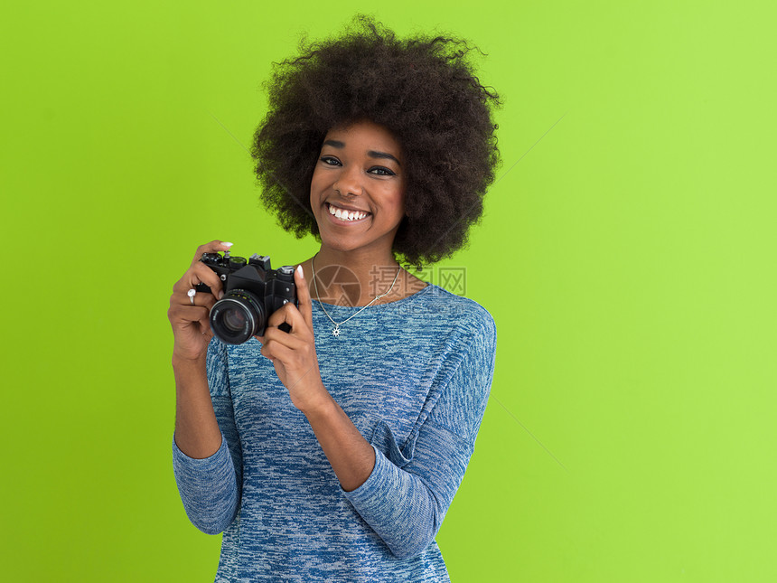 位微笑的漂亮非裔美国女孩的肖像,绿色背景上隔离的复古相机上拍照图片