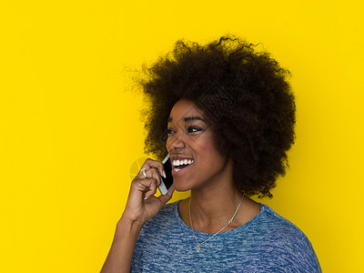 轻快乐的非裔美国妇女用手机隔离黄色背景上图片