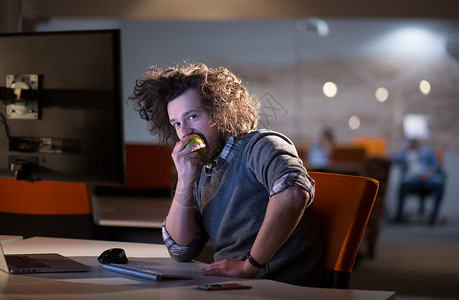 创造力的人正他的夜办公室工作,吃苹果图片