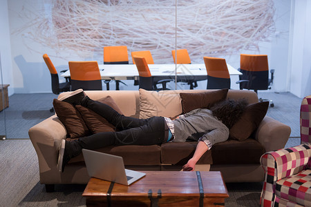 位轻的休闲商人创意办公室休息时睡沙发上图片