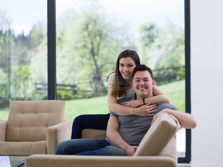 轻英俊的夫妇喜欢他们豪华的家庭别墅的沙发上拥抱图片