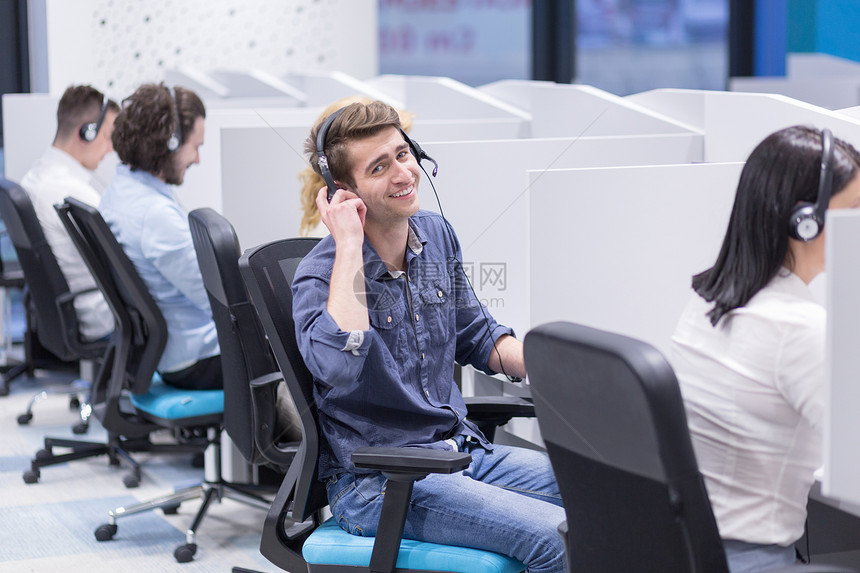 群带耳机的轻人呼叫中心办公室工作并为客户提供支持图片