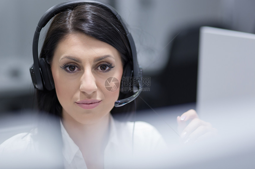 轻微笑的女呼叫中心接线员用耳机她的工作图片
