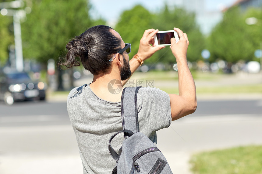 休闲,技术人的时髦的男人街上用智能手机拍照录像图片