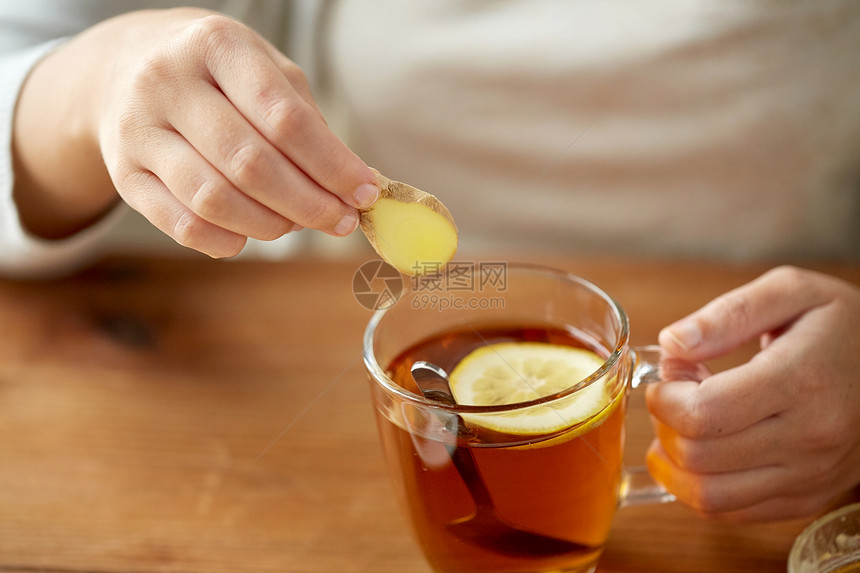健康,传统医学民族科学的密切妇女添加生姜茶杯与柠檬图片