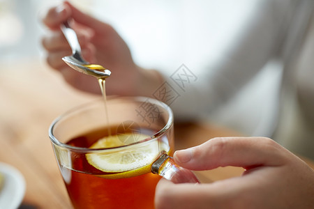 健康食品,饮食民族科学的密切妇女添加蜂蜜与柠檬茶杯图片