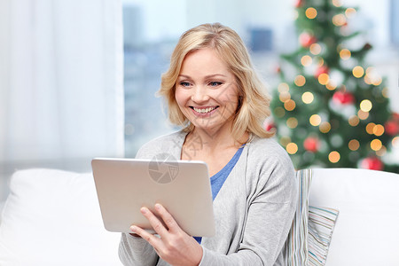 人,技术,假日互联网快乐的中妇女与平板电脑家里的诞树灯光背景图片