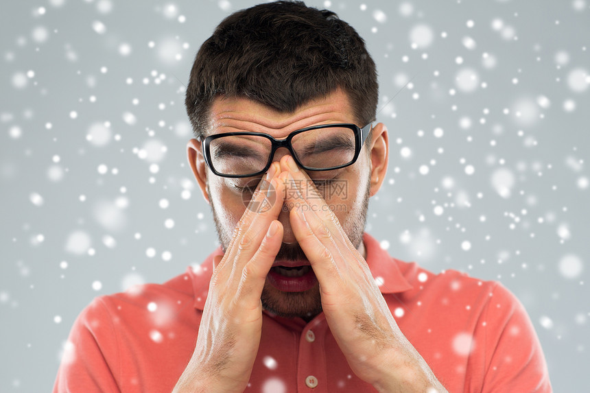 商业,人,视觉,冬天过度劳累的疲惫的男人戴着眼镜,灰色背景下摸着雪上的鼻梁图片