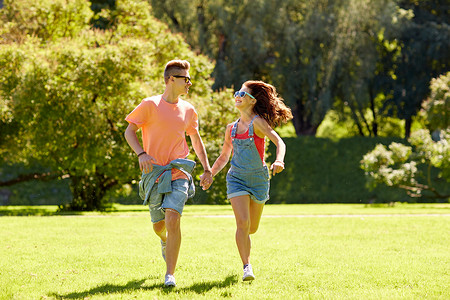 假期,爱人的快乐的微笑十几岁的夫妇牵着手,夏季公园跑步图片