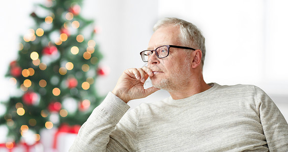 老人,假期,问题人的戴眼镜的老人家里思考诞树的背景图片