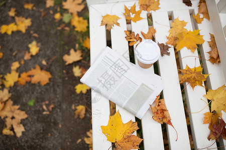 公报季节新闻报纸咖啡杯秋天公园的长凳上秋天公园长凳上的报纸咖啡杯背景