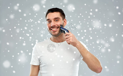 美丽,修饰,冬天,诞节人们的微笑的轻人刮胡子与修剪电动剃须刀雪上的灰色背景图片