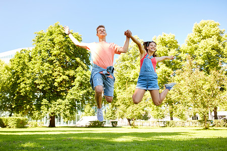 假期,爱人的快乐的微笑青少夫妇夏季公园跳跃图片