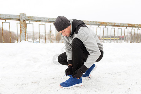 健身,运动,人,音乐健康的生活方式轻人戴着耳机冬季桥上系鞋背景图片
