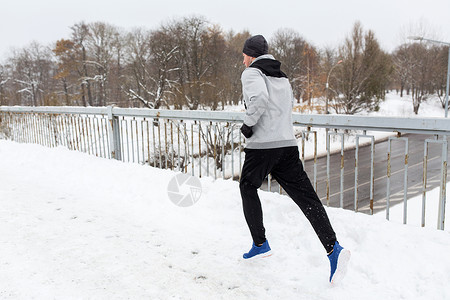 健身,运动,人,音乐健康的生活方式轻人戴着耳机沿着雪覆盖的冬季桥梁跑步图片