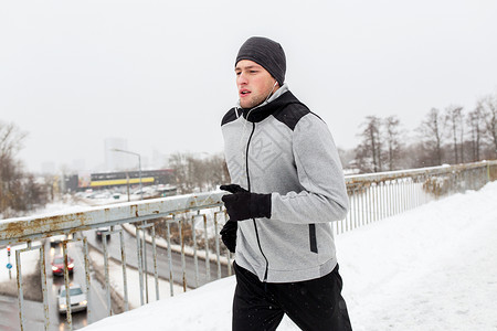 健身,运动,人,音乐健康的生活方式轻人戴着耳机沿着雪覆盖的冬季桥梁跑步图片