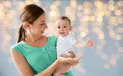 家庭,孩子父母的快乐的微笑轻母亲与小婴儿假期灯光背景图片