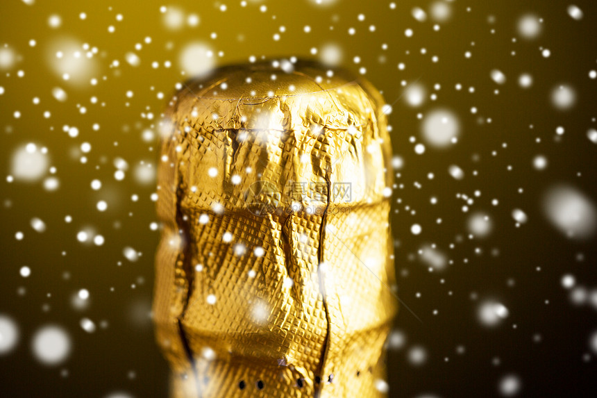 饮料,酒精,诞节,新寒假的香槟瓶软木塞顶部包裹成金箔黑暗的背景与雪图片