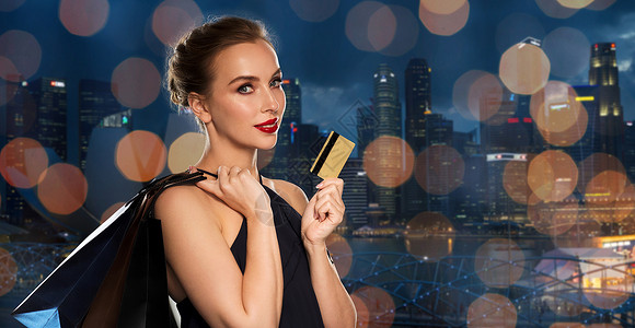城市信用卡人,豪华销售美丽的女人与信用卡购物袋过夜新加坡城市摩天大楼灯光背景背景
