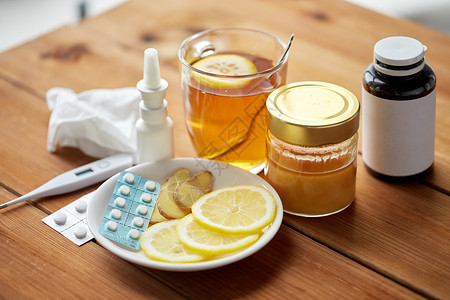 医疗保健,传统医学流感药物,温度计,蜂蜜木制桌子上的杯茶图片