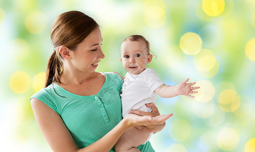 家庭,孩子父母的快乐的微笑轻母亲与小婴儿绿色假日灯光背景图片
