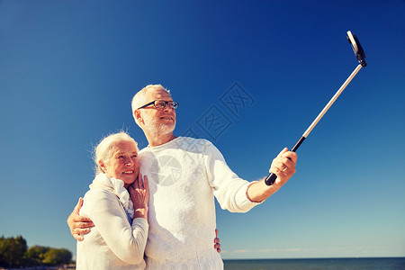 龄,旅游,技术人的快乐的老夫妇与智能手机自拍杆拍照夏季海滩图片