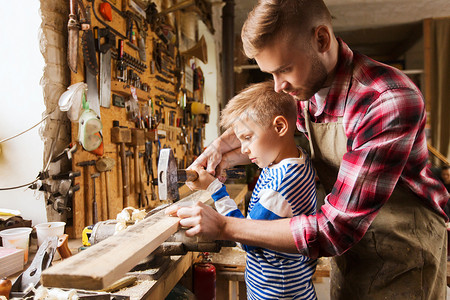 家庭,木工,木工人的父亲小儿子用锤击钉子车间的木板上背景图片