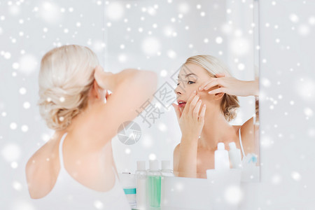 美丽,卫生,皮肤问题人的轻的女人看着镜子,家里的浴室里挤着粉刺图片
