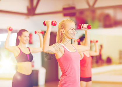 健身,运动,训练,健身房生活方式的群微笑的女人健身房里用哑铃锻炼图片
