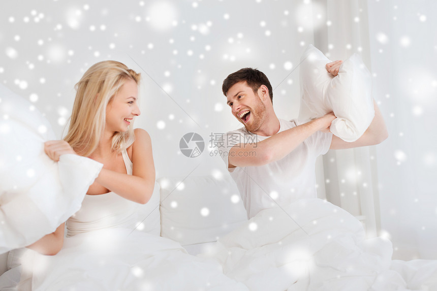 人们,家庭,睡觉时间趣的幸福的夫妇雪地上的床上打枕头战图片