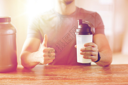 运动,健身,健康的生活方式人们的近距离的人健身手镯与蛋白质瓶大拇指图片