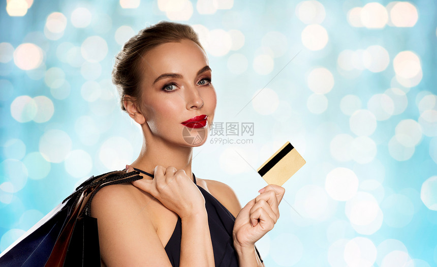 人,豪华销售美丽的女人与信用卡购物袋蓝色假日灯光背景图片