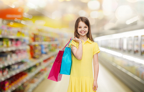 销售,儿童人的微笑的小女孩穿着黄色连衣裙,超市背景下购物袋图片