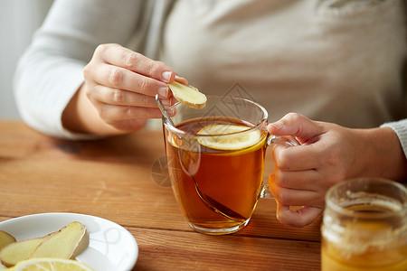 健康,传统医学民族科学的密切妇女添加生姜茶杯与柠檬蜂蜜图片