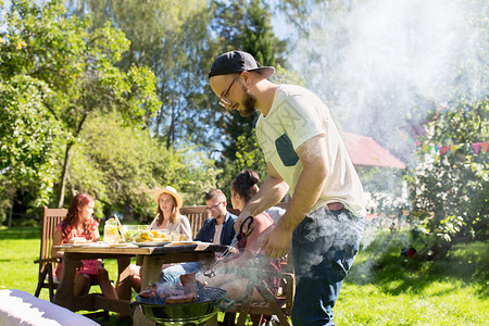 休闲,食物,人假日的男子烹饪肉烧烤为他的朋友夏季户外聚会图片
