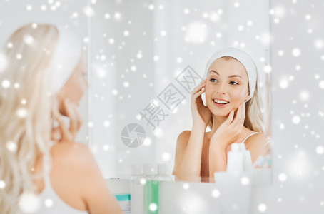 美丽,皮肤护理人的微笑的轻女人发带触摸她的脸,并家里的浴室雪地上看镜子图片